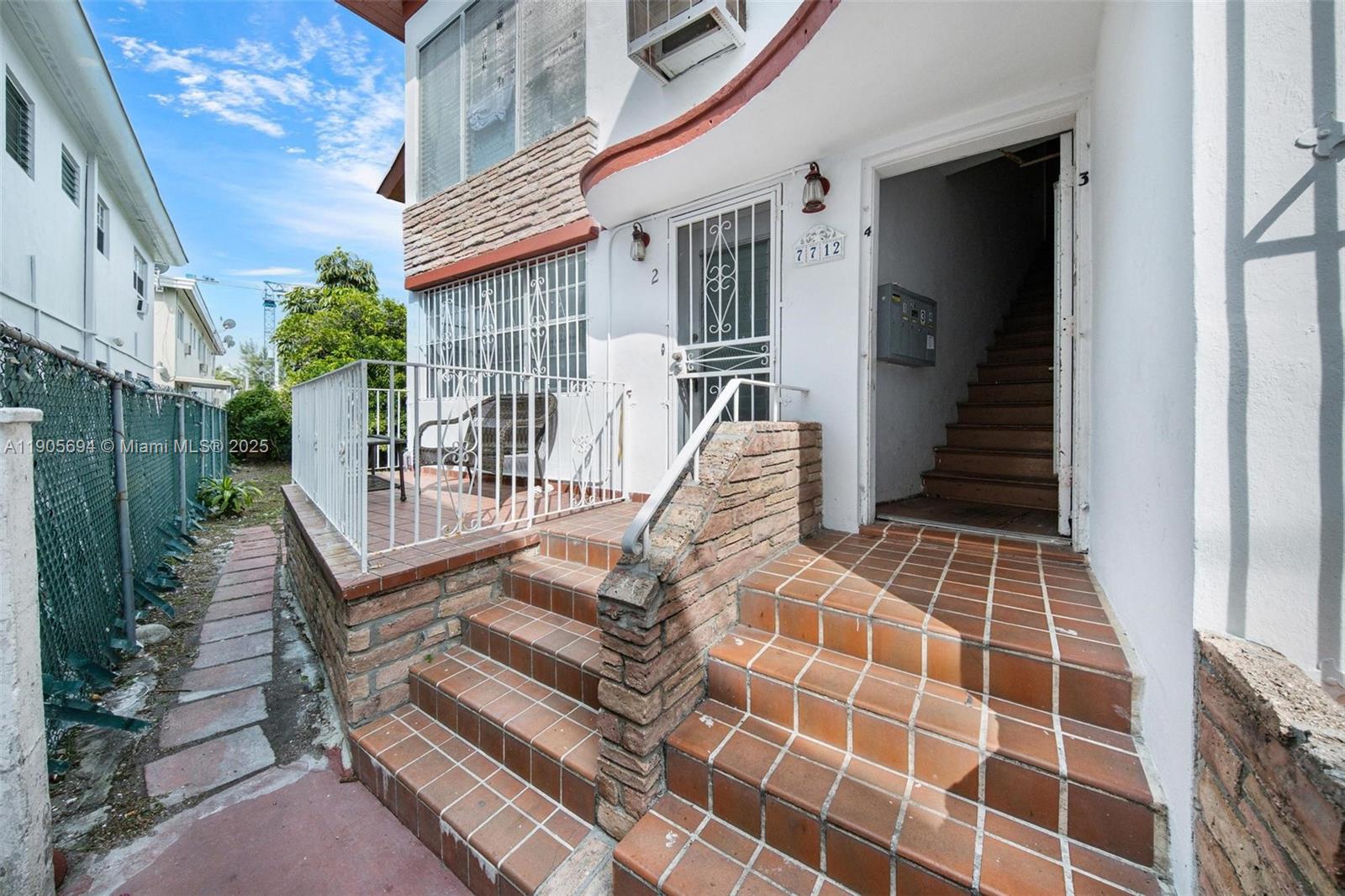 A white building exterior features a tiled staircase leading to a doorway and a patio — 7712 Byron Ave # 2, Miami Beach FL 33141, MIAMI BEACH, FL