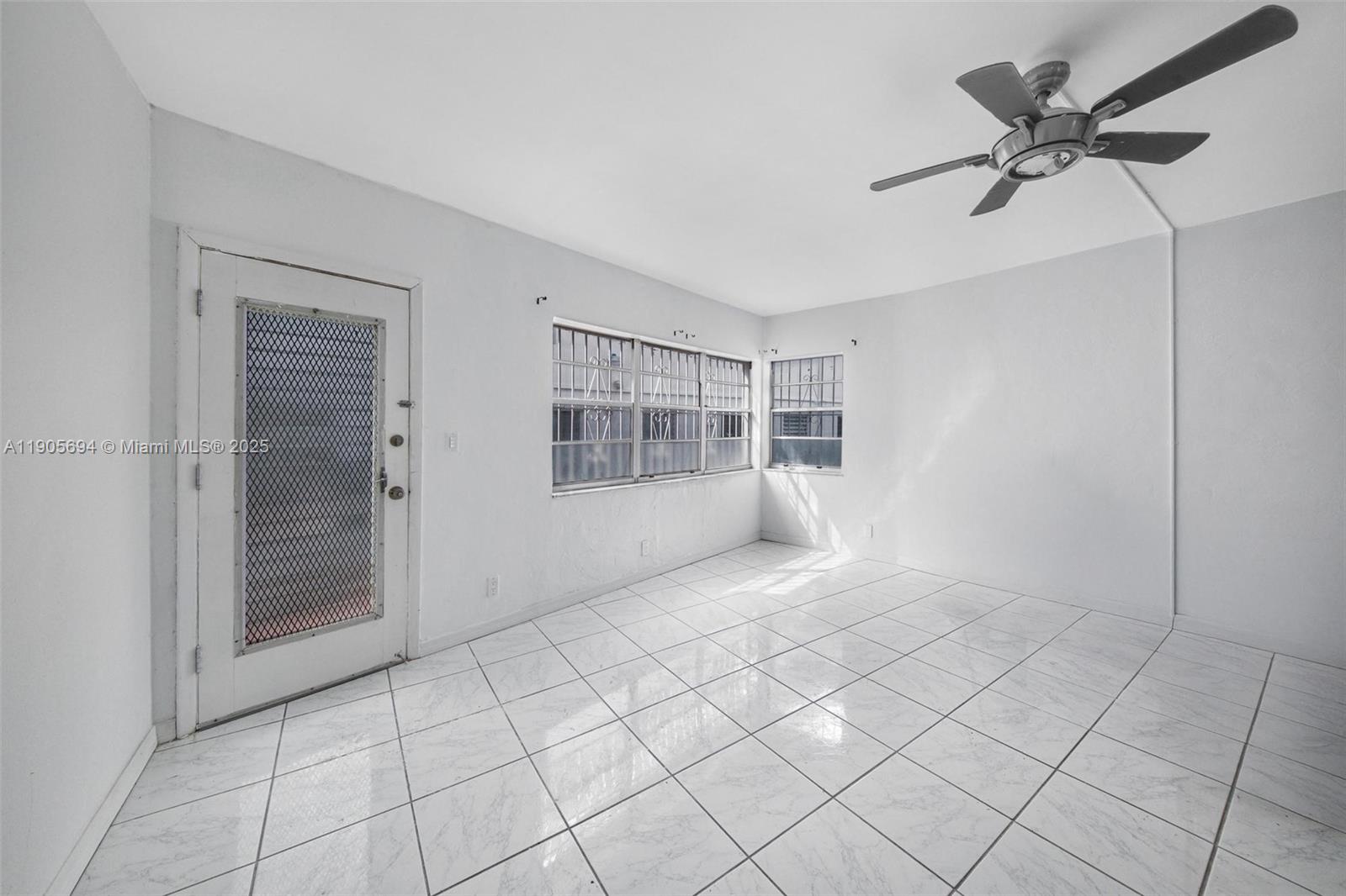 A room with white tiled floors, white walls, a ceiling fan, and barred windows — 7712 Byron Ave # 2, Miami Beach FL 33141, MIAMI BEACH, FL
