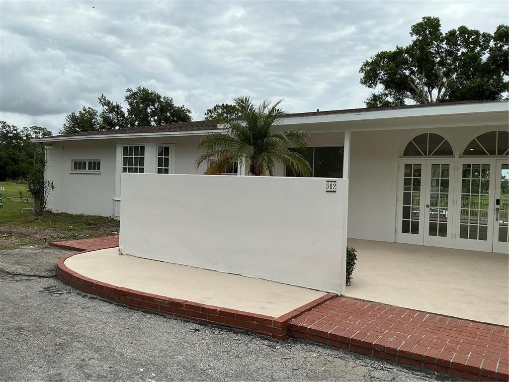 A white exterior wall stands on a paved patio in front of a house entrance — 502 MAGELLAN DRIVE, SARASOTA, FL