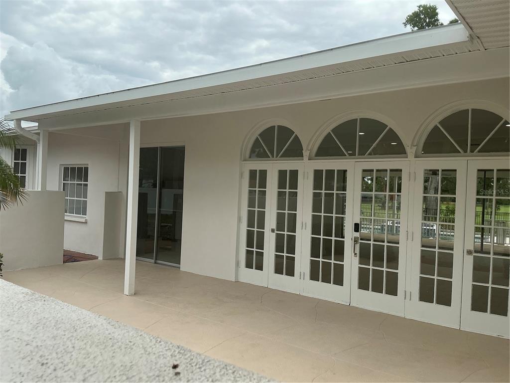 A covered patio features white walls, a concrete floor, and multiple glass-paned French doors — 502 MAGELLAN DRIVE, SARASOTA, FL