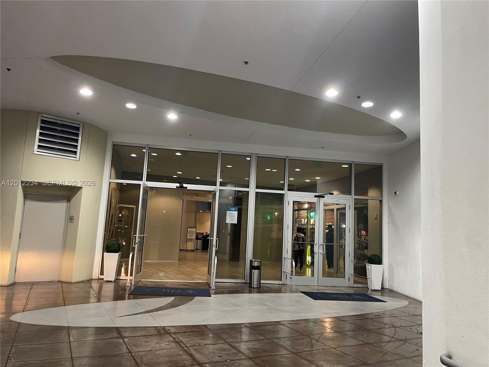 The exterior entrance of a building features glass doors, tiled flooring, and recessed ceiling lighting — 1750 N Bayshore Dr # 3403, Miami FL 33132, MIAMI, FL
