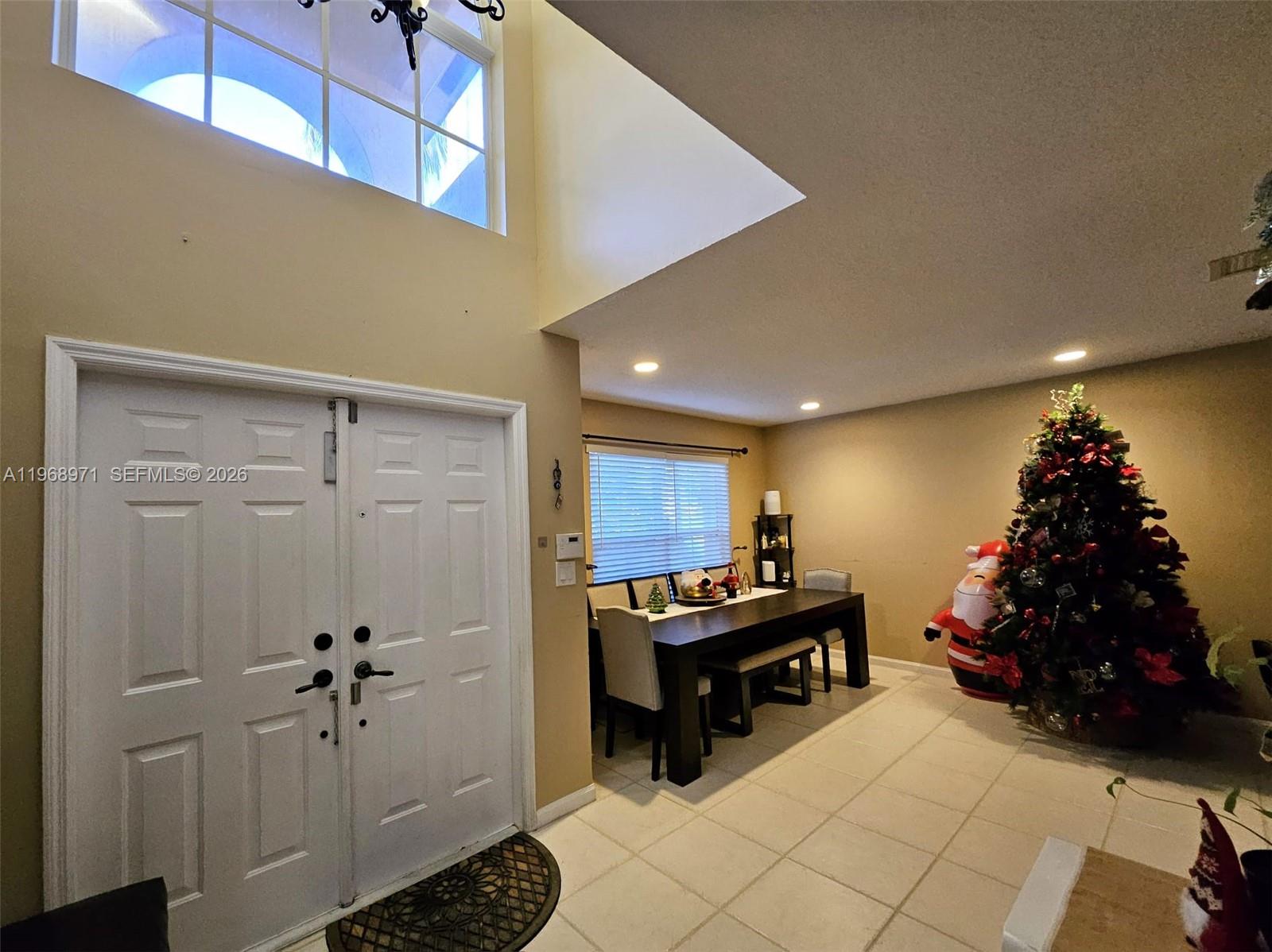 A dining area with a Christmas tree sits near a double-door entryway with high ceilings — 14070 S Forest Oak Cir, Davie FL 33325, DAVIE, FL