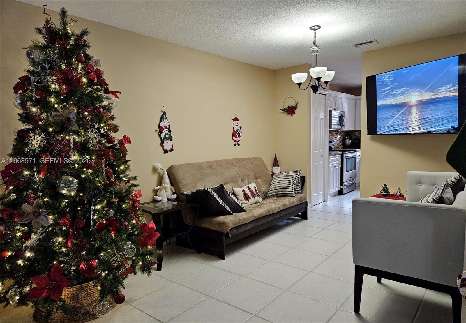 A living room features a Christmas tree, a futon, a television, and tiled flooring — 14070 S Forest Oak Cir, Davie FL 33325, DAVIE, FL