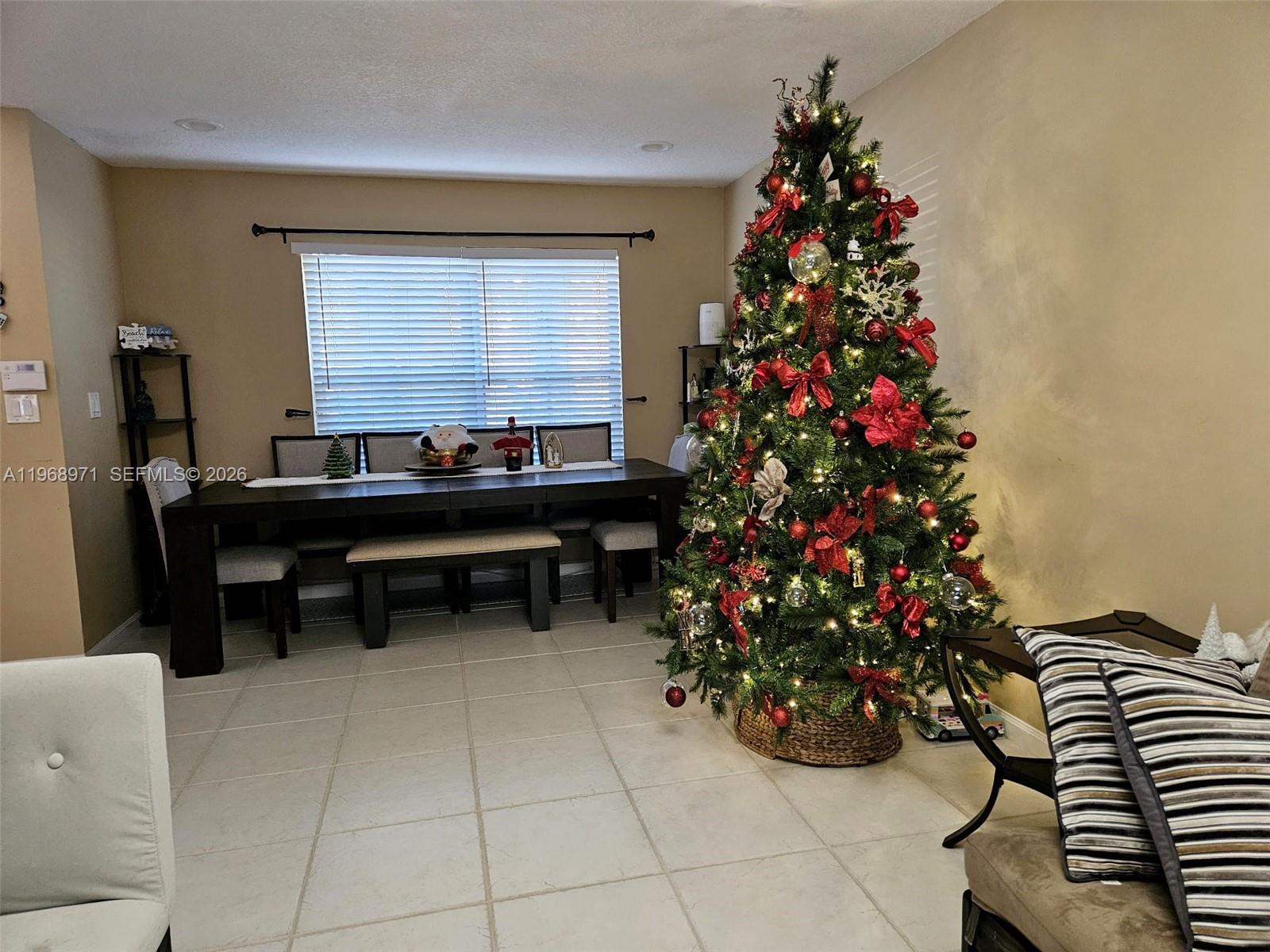 A dining room features a long dark table, a large Christmas tree, and tiled floors — 14070 S Forest Oak Cir, Davie FL 33325, DAVIE, FL