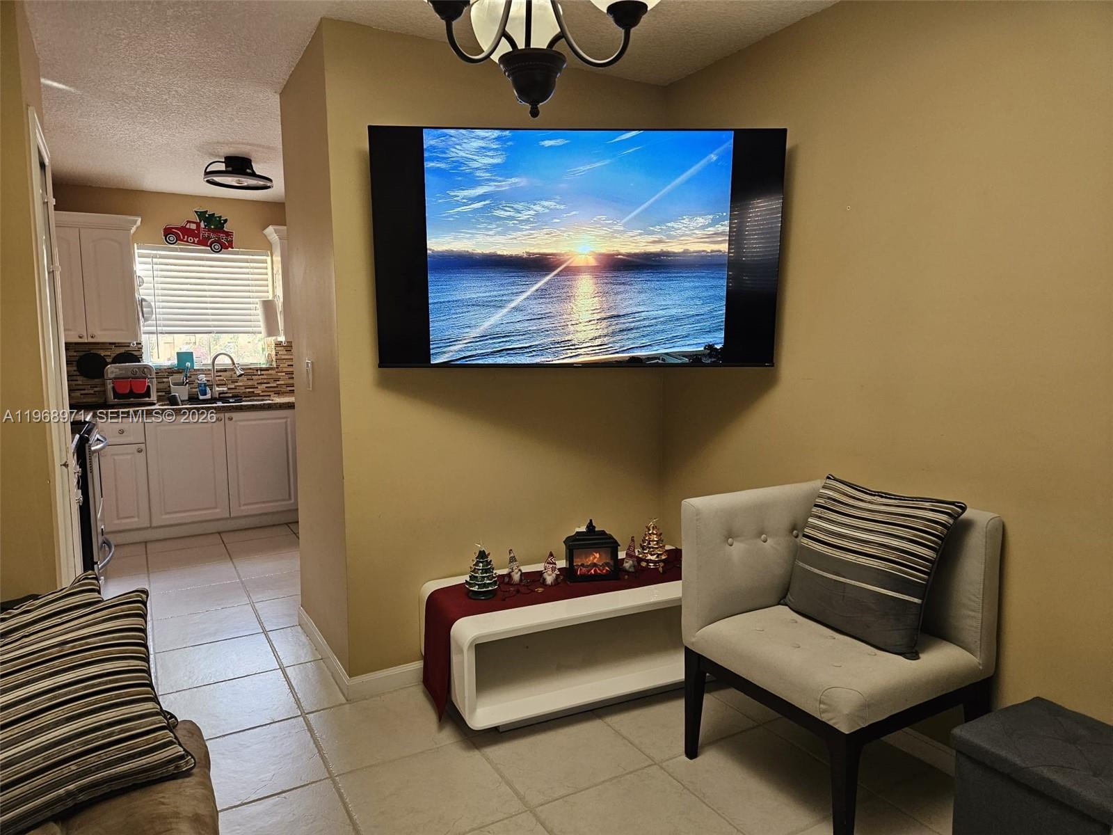 A living area features a wall-mounted television above a low white console and an armchair — 14070 S Forest Oak Cir, Davie FL 33325, DAVIE, FL