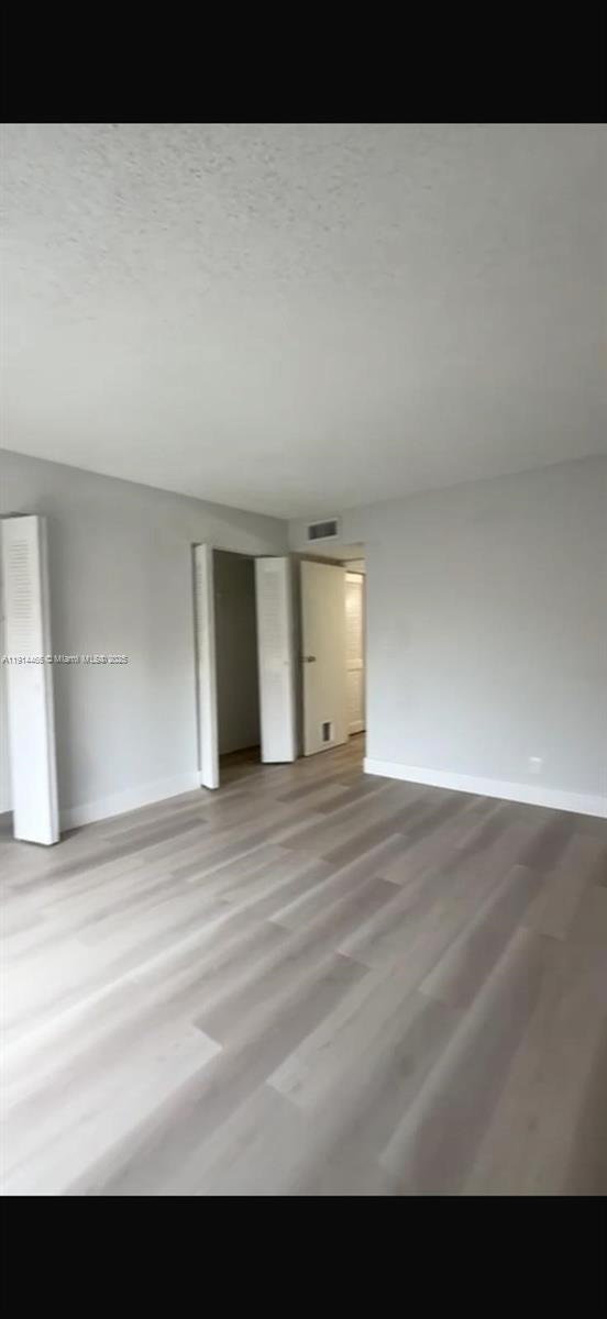 An empty room with light gray walls and light-colored wood-look flooring — 17901 NW 68 Ave # 205, Hialeah FL 33015, HIALEAH, FL