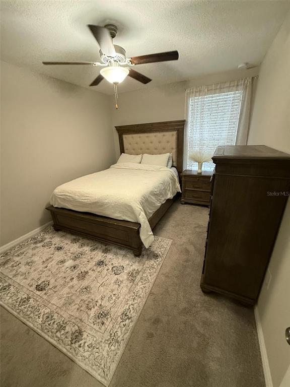 A bedroom features a tufted headboard bed, a wooden dresser, and a ceiling fan — 10364 ALDER GREEN DRIVE, RIVERVIEW, FL