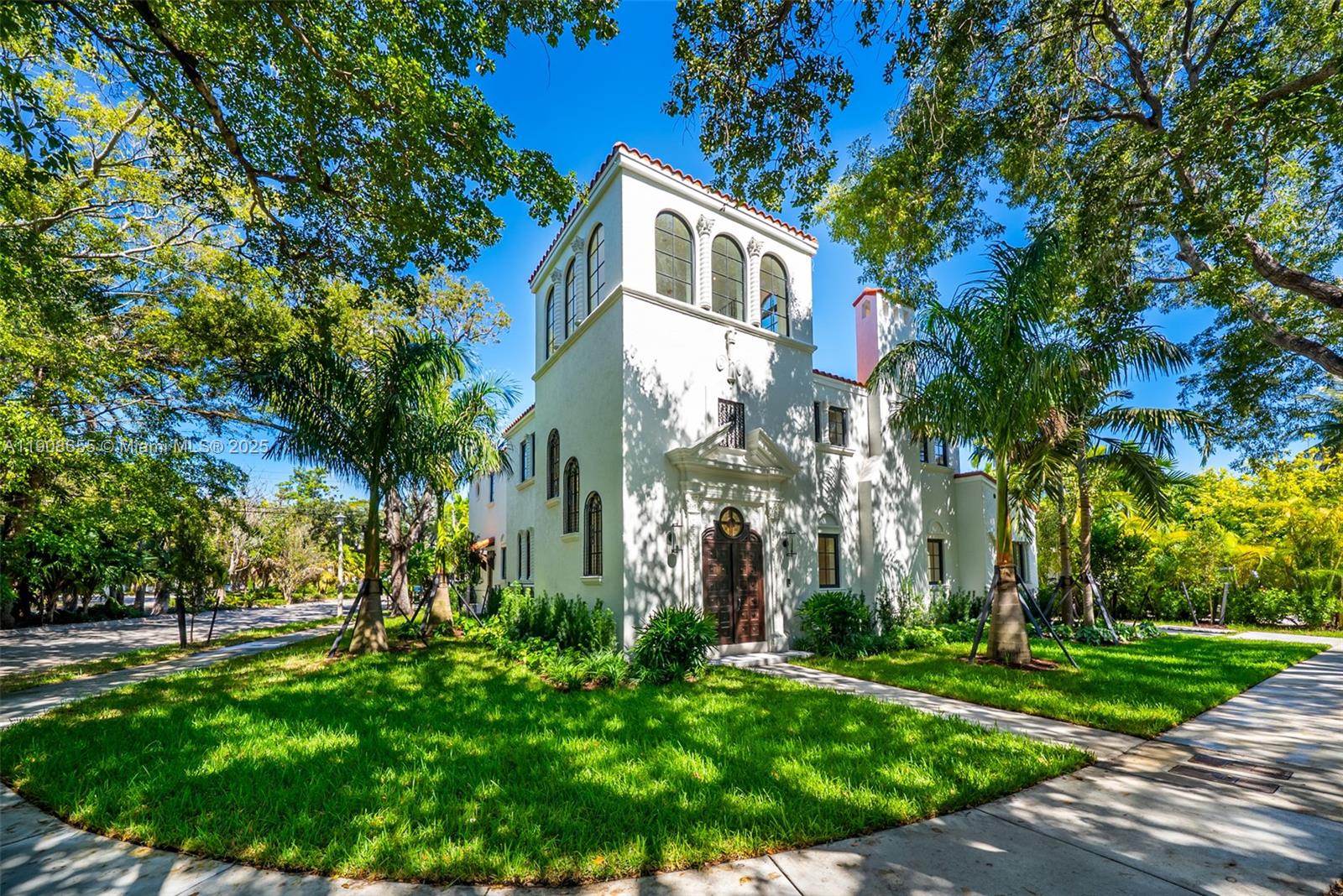 A white Mediterranean-style house with a prominent tower stands among trees and a green lawn — 601 NE 56th St, Miami FL 33137, MIAMI, FL
