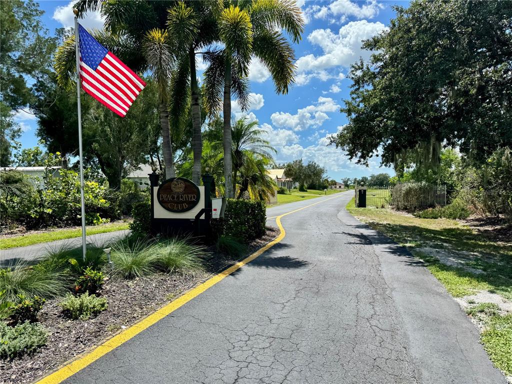 An American flag flies next to a sign for Peace River Club at a driveway entrance — 530 WOODSTORK LANE, PUNTA GORDA, FL