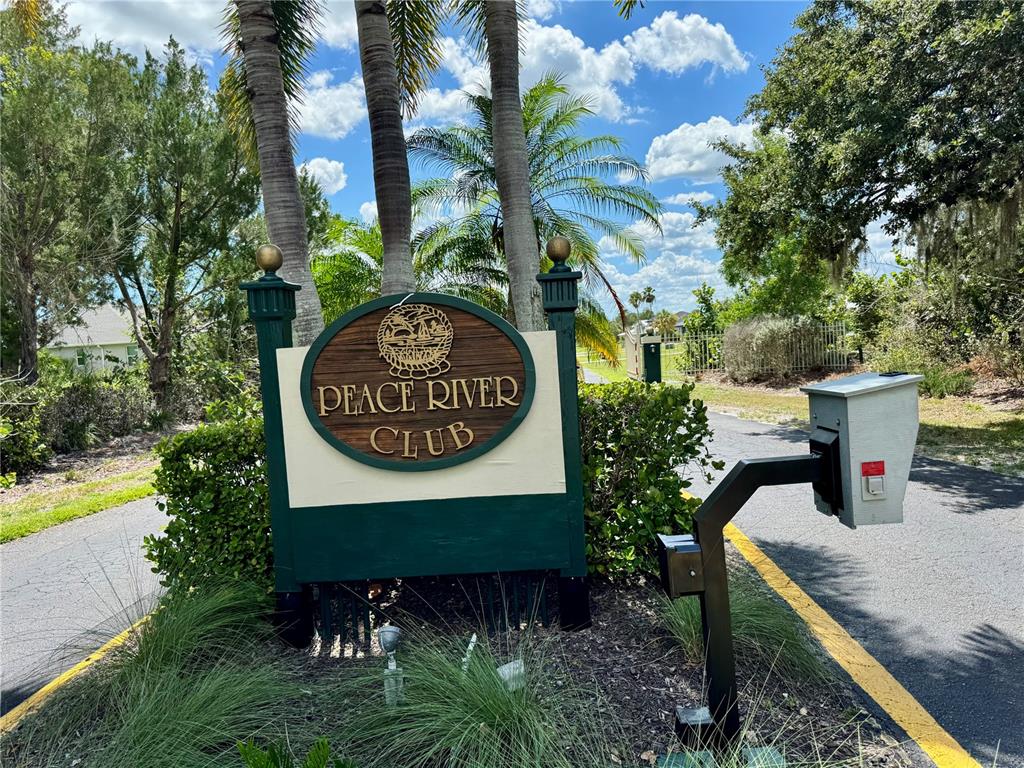 A sign for the Peace River Club stands at the entrance to a paved road — 530 WOODSTORK LANE, PUNTA GORDA, FL