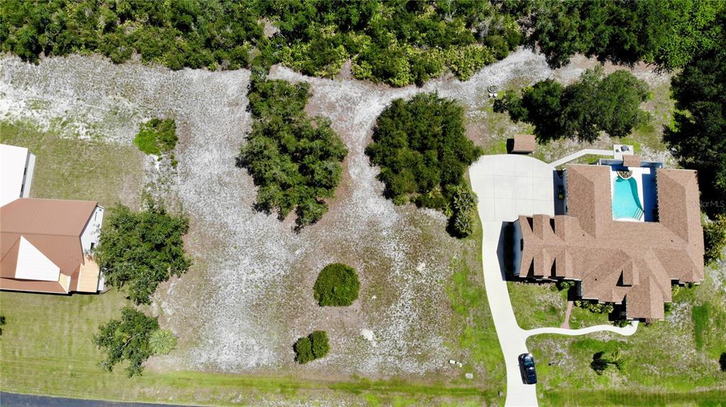 An aerial view shows a large, vacant lot situated between two residential houses — 530 WOODSTORK LANE, PUNTA GORDA, FL