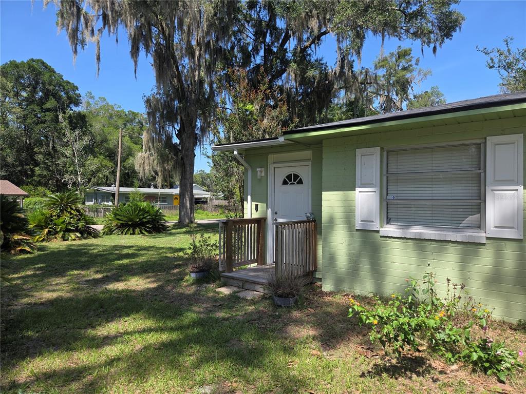 A light green house exterior features a white front door, wooden porch, and window shutters — 725 NW 33RD AVENUE, GAINESVILLE, FL