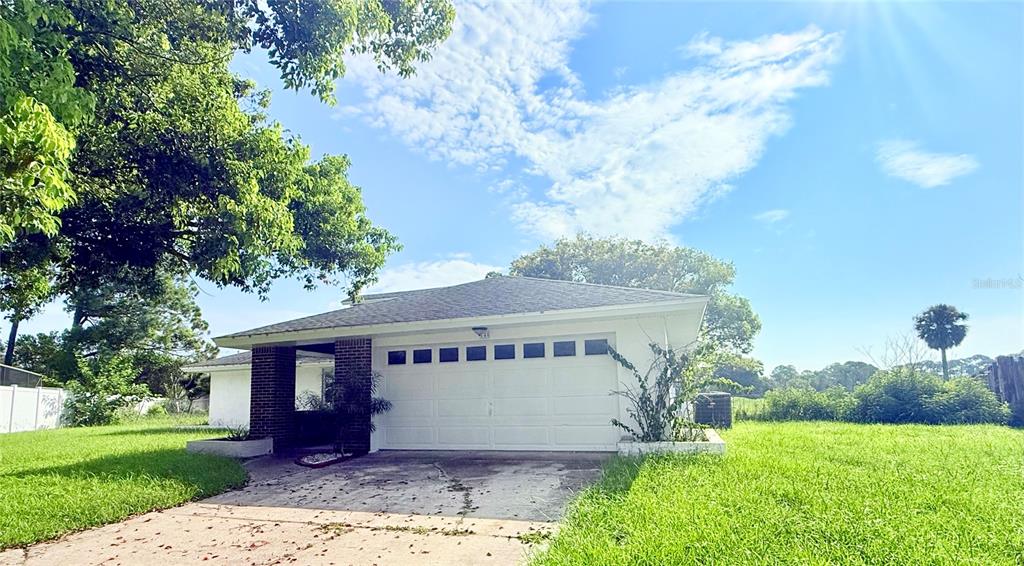 A single-story house with a white garage door and a brick-accented entryway — 140 FAIRWAY TEN DRIVE, CASSELBERRY, FL