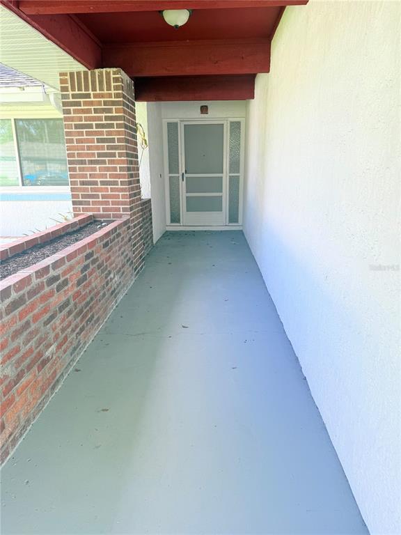 A covered porch features a brick planter, a painted concrete floor, and a front door — 140 FAIRWAY TEN DRIVE, CASSELBERRY, FL
