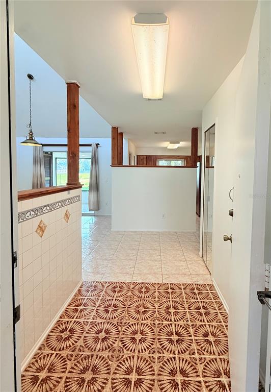 An entryway with patterned tile flooring leads into a living area with light-colored floor tiles — 140 FAIRWAY TEN DRIVE, CASSELBERRY, FL
