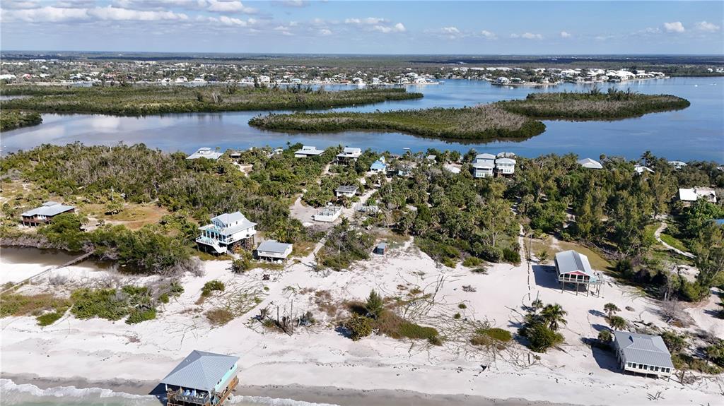 An aerial view shows several elevated beach houses situated along a sandy coastline near mangroves — 8092 LITTLE GASPARILLA ISLAND, PLACIDA, FL