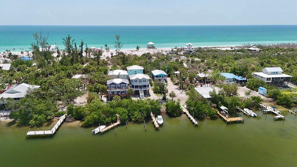 An aerial view shows several coastal houses situated between a calm bay and the ocean — 8092 LITTLE GASPARILLA ISLAND, PLACIDA, FL
