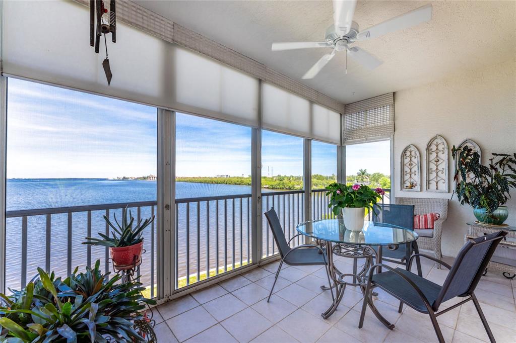 A screened-in balcony with tile flooring, a glass dining table, and a water view — 200 HARBOR WALK DRIVE UNIT 233, PUNTA GORDA, FL