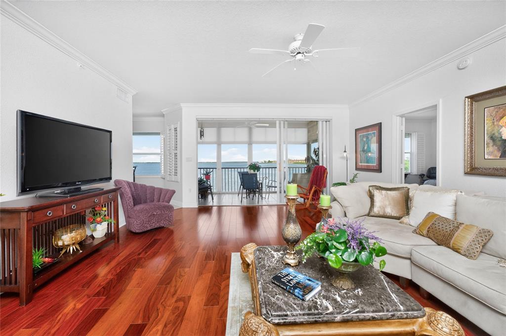 A living room with hardwood floors, a television, a sofa, and a view of water — 200 HARBOR WALK DRIVE UNIT 233, PUNTA GORDA, FL
