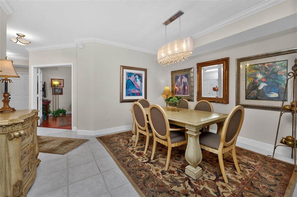 A dining room features a wooden table with six chairs, a chandelier, and wall art — 200 HARBOR WALK DRIVE UNIT 233, PUNTA GORDA, FL