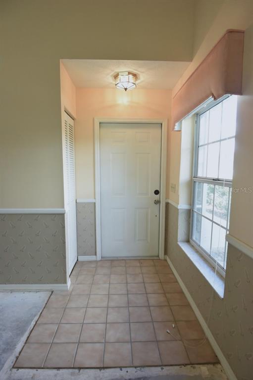 An entryway features a tiled floor, a white front door, and walls with patterned wallpaper — 2401 SW 20TH COURT, OCALA, FL