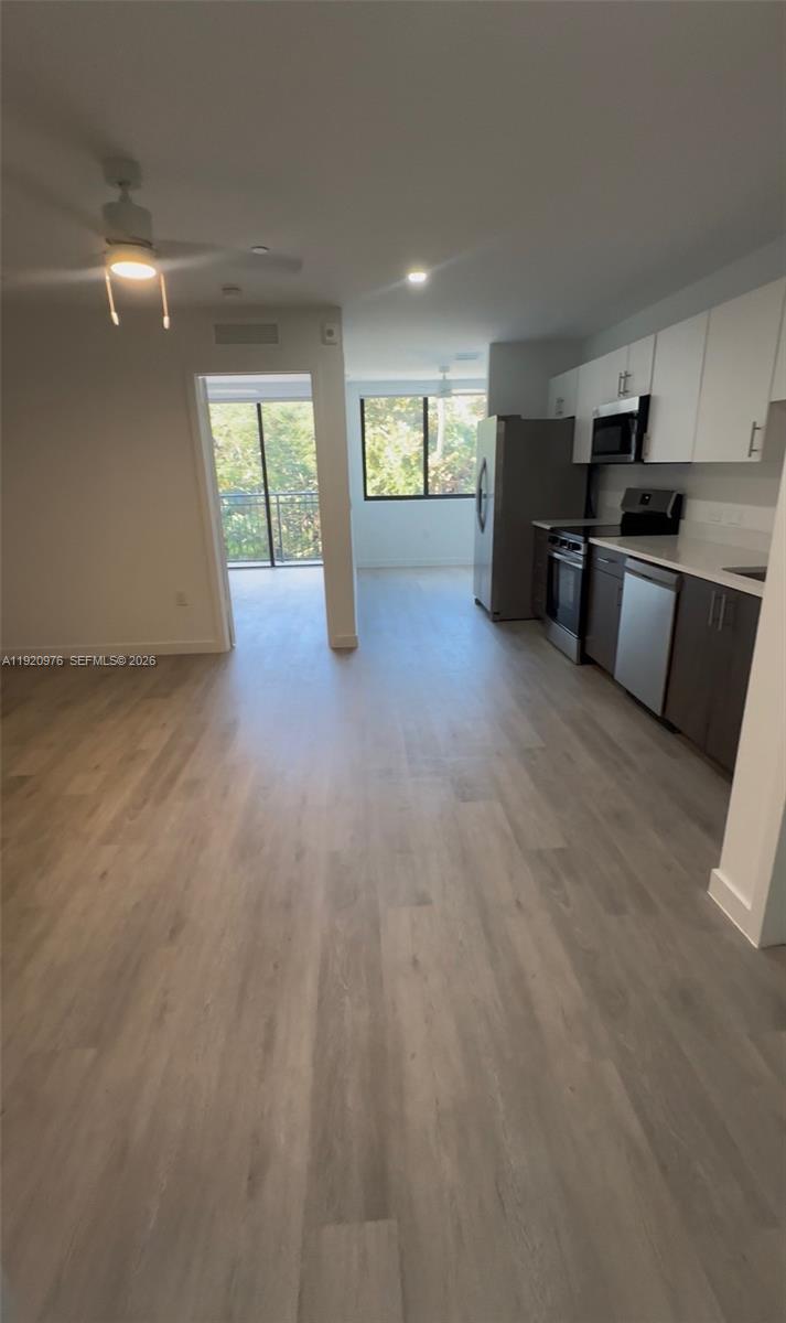 This kitchen and living area features light wood-look flooring, white upper cabinets, and dark lower cabinets — 20 NE 19th Ave # 302, Pompano Beach FL 33060, POMPANO BEACH, FL