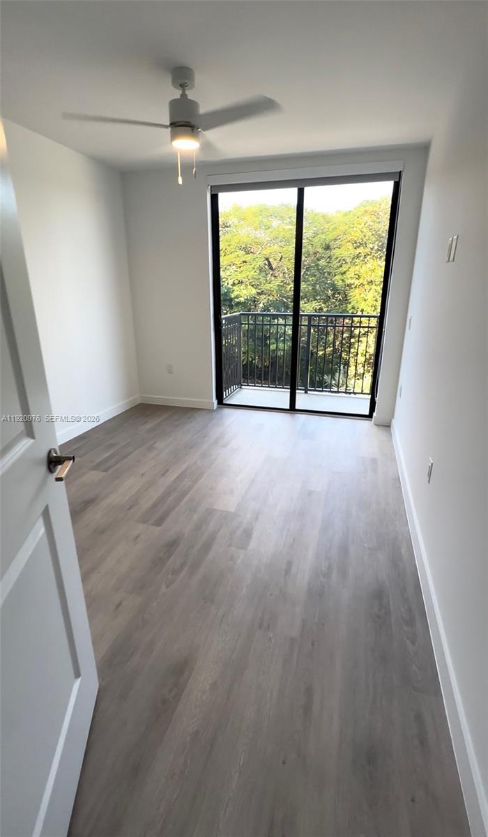 A bedroom features light wood-look flooring, a ceiling fan, and a balcony with tree views — 20 NE 19th Ave # 302, Pompano Beach FL 33060, POMPANO BEACH, FL