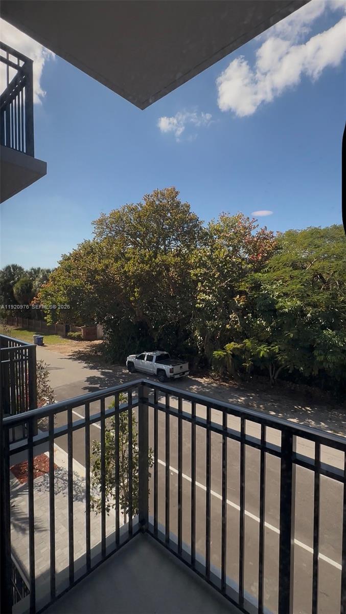 A view from a balcony overlooking a street, a parked white truck, and trees — 20 NE 19th Ave # 302, Pompano Beach FL 33060, POMPANO BEACH, FL