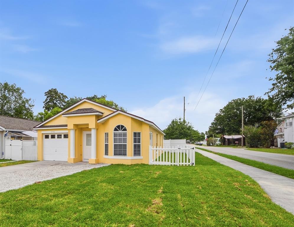 A yellow single-story house with a white garage door and a white picket fence — 2741 S BROWN AVENUE, ORLANDO, FL