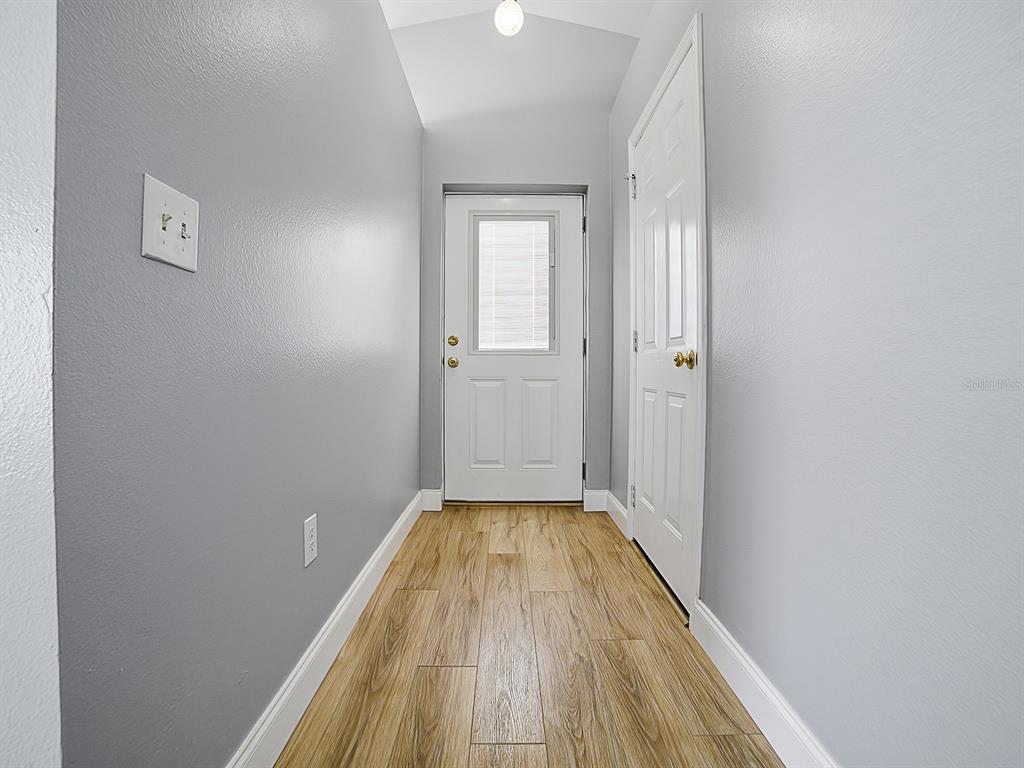 A hallway with light gray walls, wood-look flooring, a white door, and a closet door — 2741 S BROWN AVENUE, ORLANDO, FL