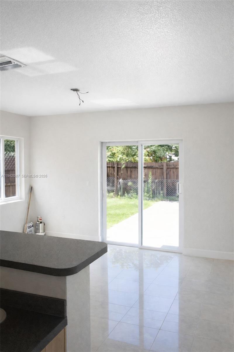A kitchen counter overlooks a bright room with tile floors and sliding glass patio doors — 16585 NE 3 AVE, Miami FL 33162, MIAMI, FL