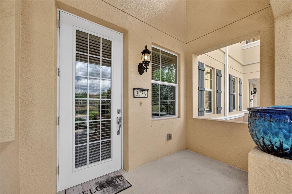 A white front door with glass panes sits next to a window on a porch — 3736 82ND AVENUE CIRCLE E UNIT 105, SARASOTA, FL