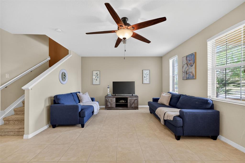 A living room features two blue sofas, a television console, and tile flooring — 3736 82ND AVENUE CIRCLE E UNIT 105, SARASOTA, FL