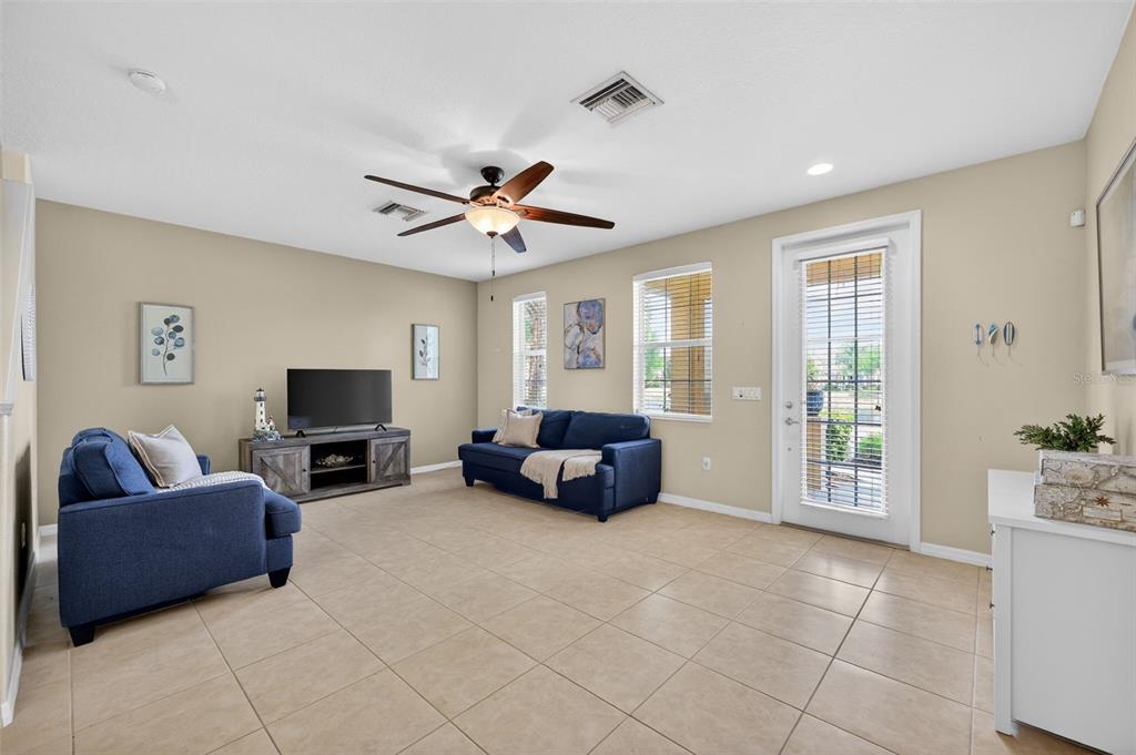 A living room with blue sofas, a television, tile flooring, and a glass-paned door — 3736 82ND AVENUE CIRCLE E UNIT 105, SARASOTA, FL