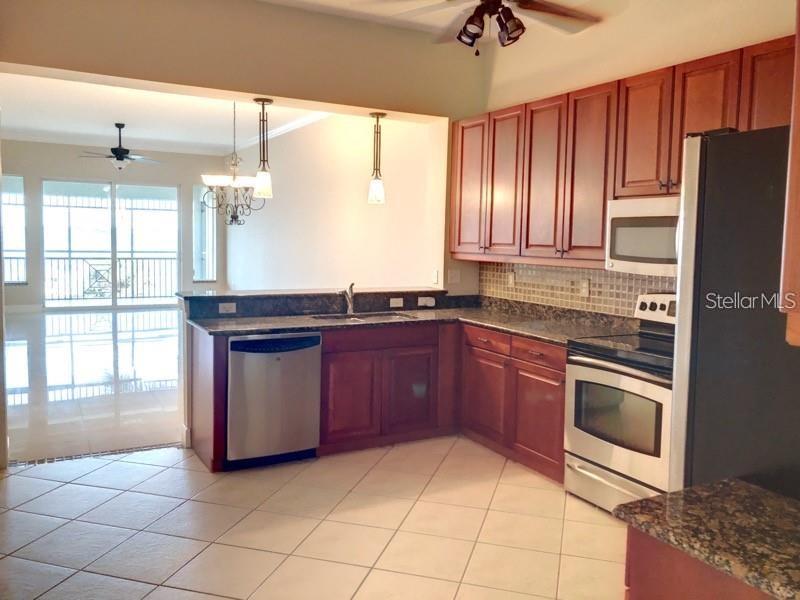 A kitchen features dark wood cabinets, stainless steel appliances, and tile flooring — 5114 MELBOURNE STREET UNIT 1301, PORT CHARLOTTE, FL