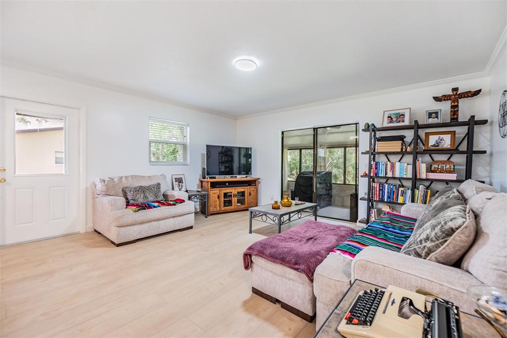 A living room with light wood floors, a sectional sofa, a bookshelf, and a television — 1400 TARPON WOODS BOULEVARD UNIT E4, PALM HARBOR, FL
