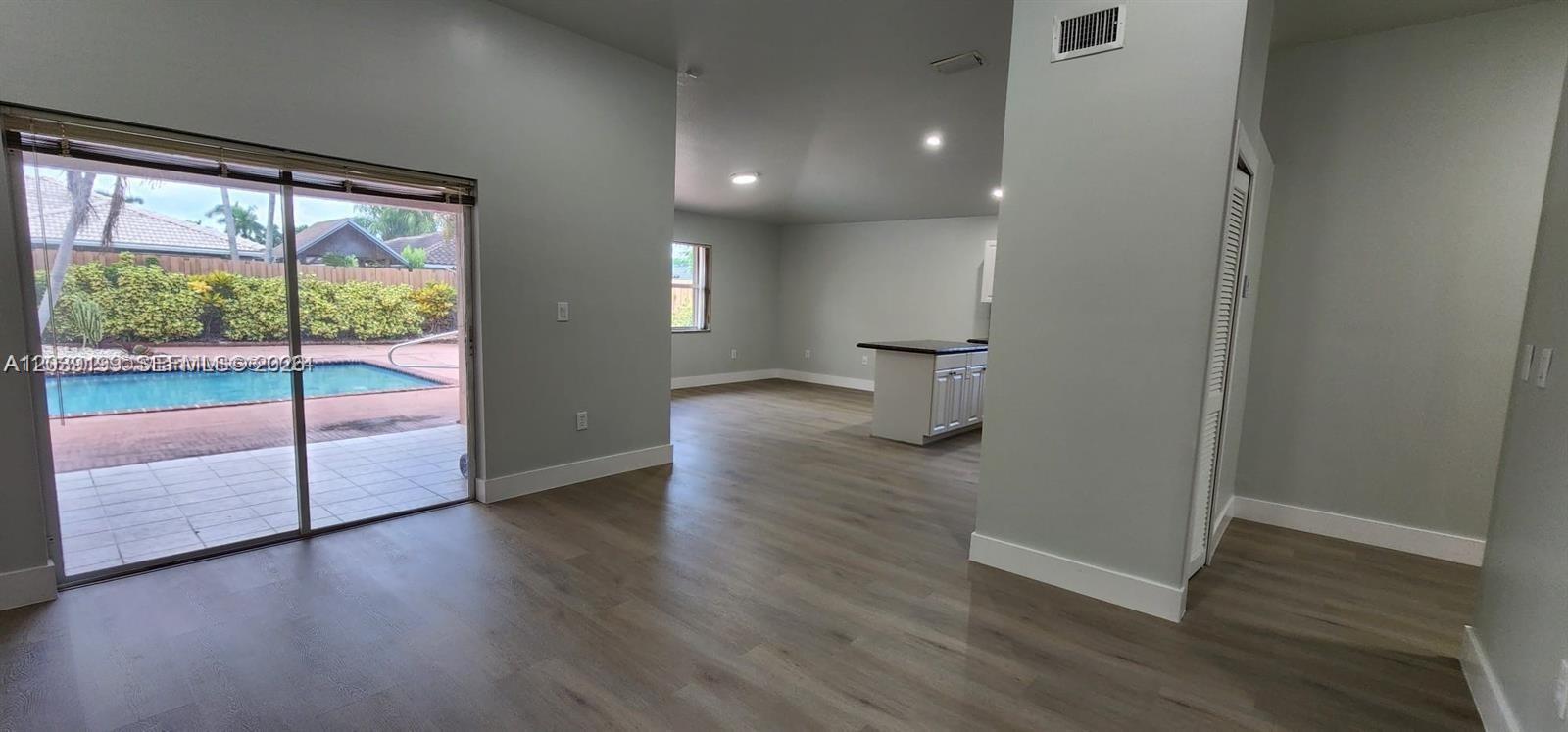A living area with light wood-look flooring opens to a patio with a swimming pool — 14817 SW 180th St, Miami FL 33187, MIAMI, FL