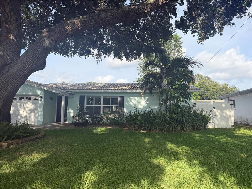 A light green single-story house features a white garage door and a paved front patio — 704 23RD STREET SW, LARGO, FL