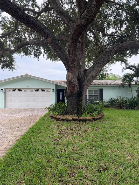 A light blue house features a paver driveway, a white garage door, and a front bench — 704 23RD STREET SW, LARGO, FL