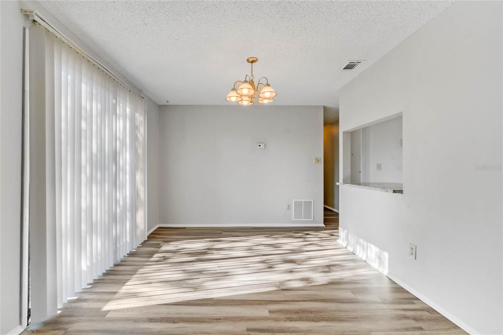 An empty dining area features light wood-look flooring, a chandelier, and a sliding glass door — 4907 LAKE RIDGE ROAD UNIT H, ORLANDO, FL