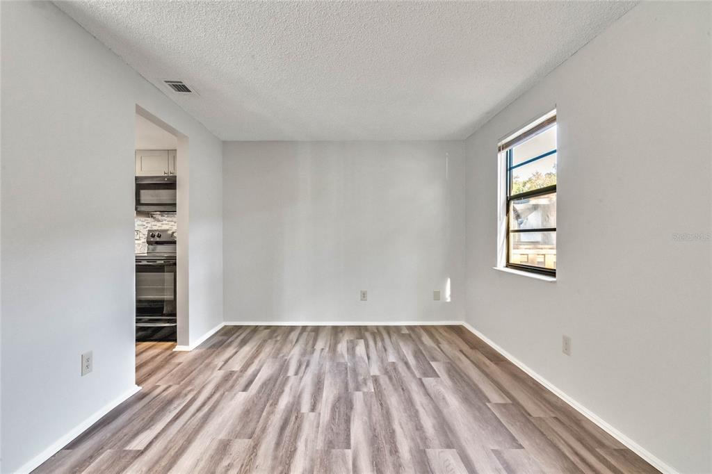 An empty room with light gray walls, wood-look flooring, and a window — 4907 LAKE RIDGE ROAD UNIT H, ORLANDO, FL