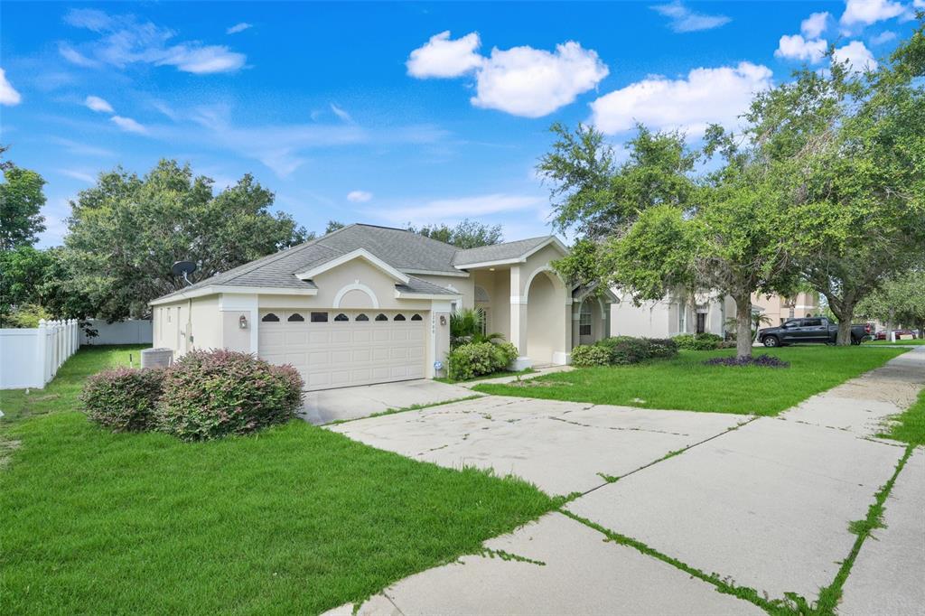 A single-story suburban house with a beige exterior, a two-car garage, and a concrete driveway — 12900 CLOVERDALE LANE, CLERMONT, FL