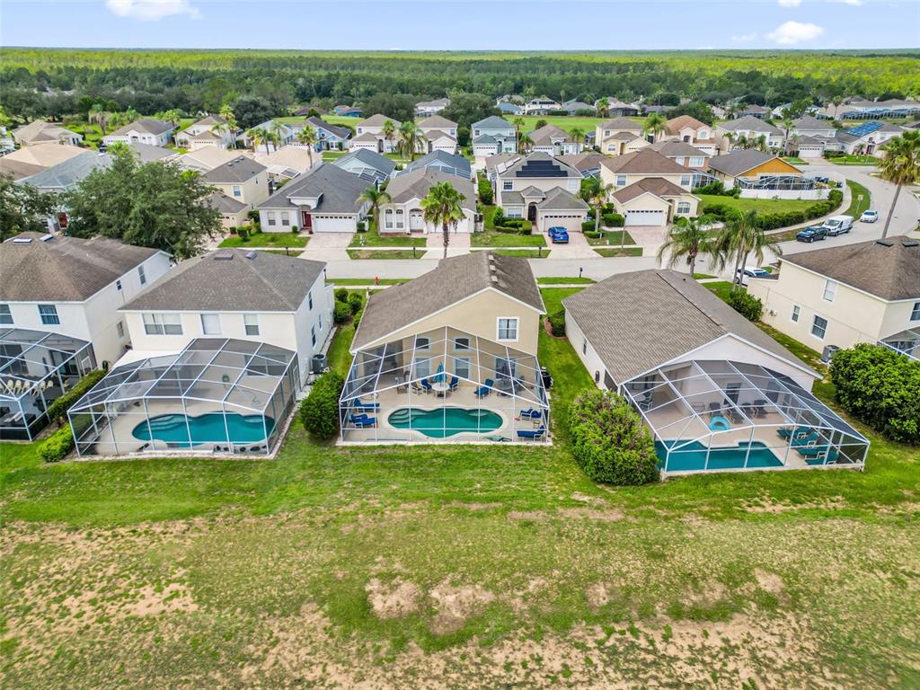 An aerial view shows three suburban houses with screened-in swimming pools in their backyards — 204 GLENEAGLES DRIVE, DAVENPORT, FL