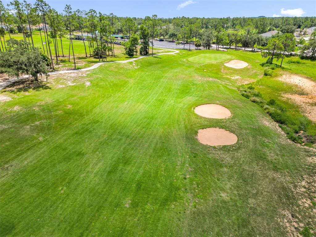 An elevated view of a golf course fairway featuring sand bunkers and surrounding trees — 204 GLENEAGLES DRIVE, DAVENPORT, FL