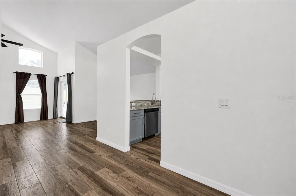 A view from a living area looking through an arched doorway into a kitchen — 204 GLENEAGLES DRIVE, DAVENPORT, FL