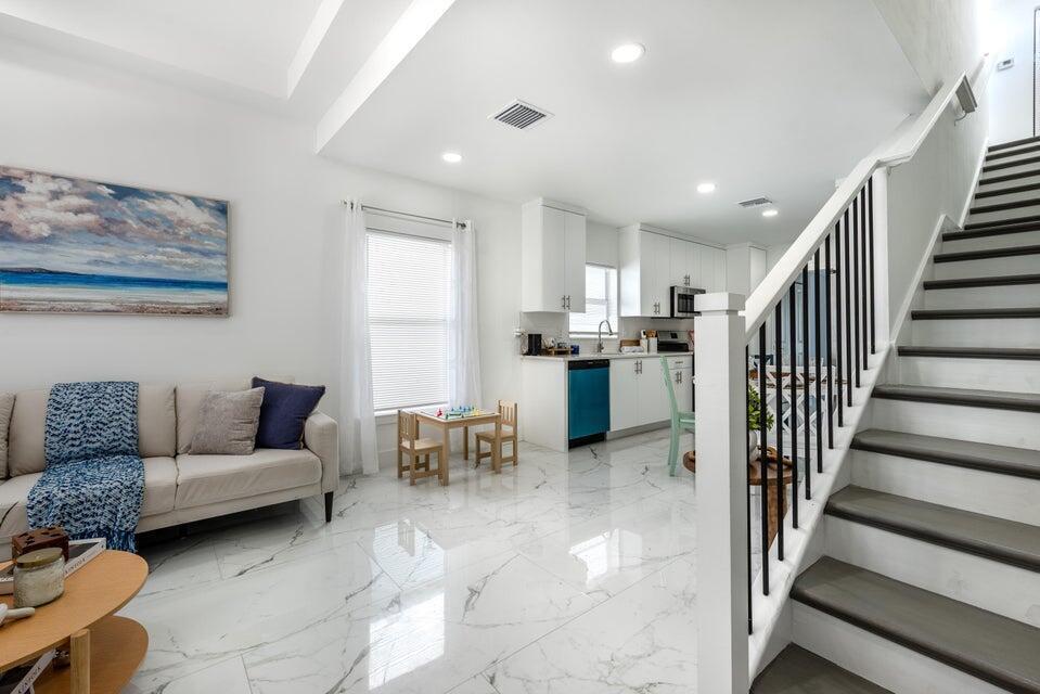 A living room with marble floors and a staircase leads to an open-concept kitchen — 425 NW 13th Avenue, Boynton Beach FL 33435, BOYNTON BEACH, FL