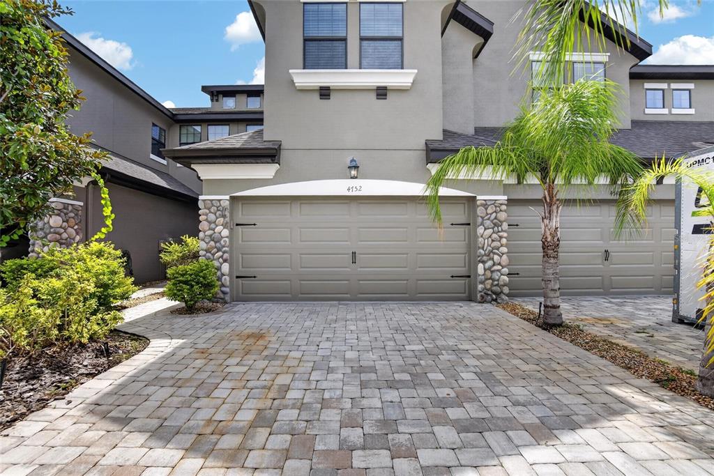 An open-concept dining area and kitchen feature wood-look tile floors and a wooden dining table — 4752 WANDERING WAY, WESLEY CHAPEL, FL