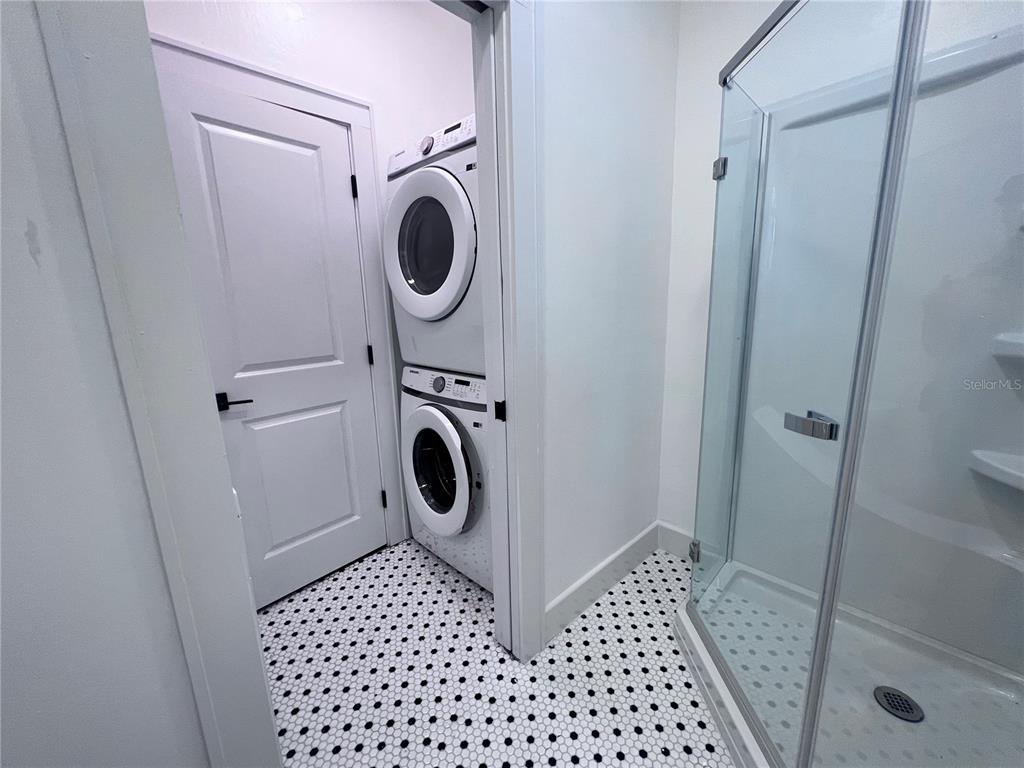 A laundry closet with a stacked washer and dryer sits next to a glass shower — 204 NW 3RD STREET, GAINESVILLE, FL