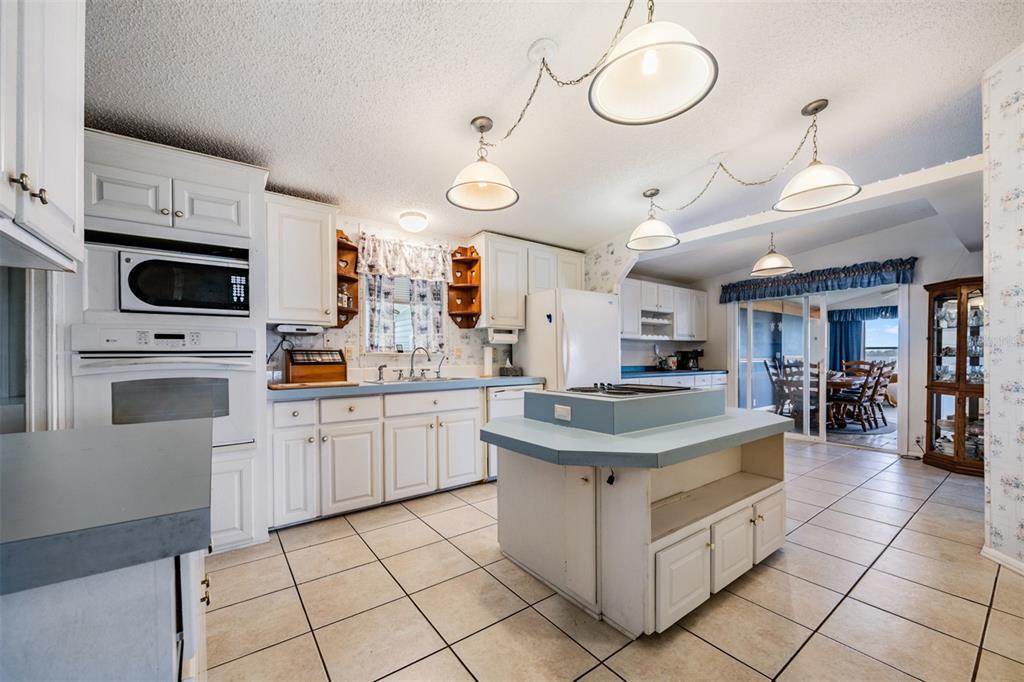 A kitchen with white cabinets, blue countertops, a central island, and tile flooring — 6827 S LAKE HENRY DRIVE NE, WINTER HAVEN, FL