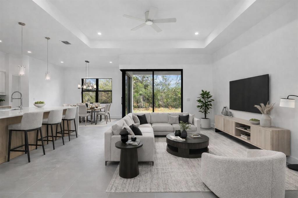 A modern open-concept living room and kitchen featuring a sectional sofa, dining area, and patio — 6192 KAMBACH STREET, PORT CHARLOTTE, FL